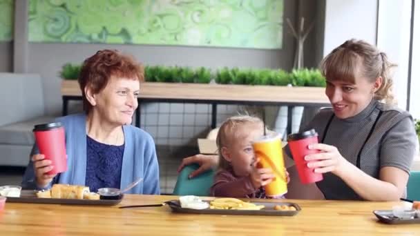 Geburtstag eines kleinen Mädchens in einem Café. Mutter und Großmutter gratulieren Mädchen mit einem Feiertag klopfen Gläser, um einen Toast zu sagen. - Filmmaterial, Video