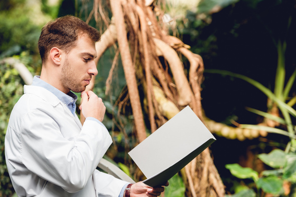 пустотливий вчений в білому пальто читає книгу в оранжереї
 - Фото, зображення