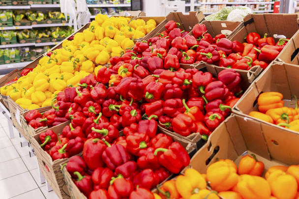 Multicolored bell peppers on the counter in the supermarket. Side view.  - 写真・画像
