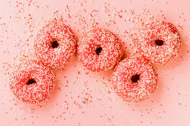 Five coral donuts lying in a line. - Zdjęcie, obraz