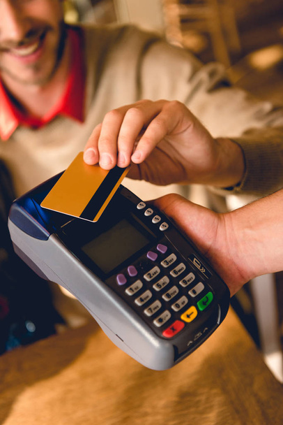 cropped view of cheerful man holding credit card while paying in cafe  - Photo, Image