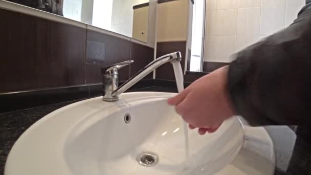 Man washing his hands in a ceramic wash basin in public restroom. - Video