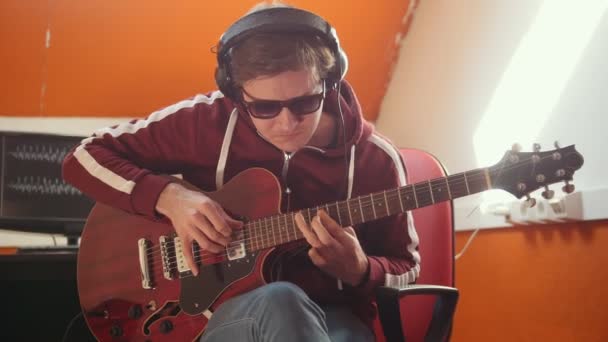 Ein Musiker mit Kopfhörern, der im Studio arbeitet. Gitarre spielen - Filmmaterial, Video