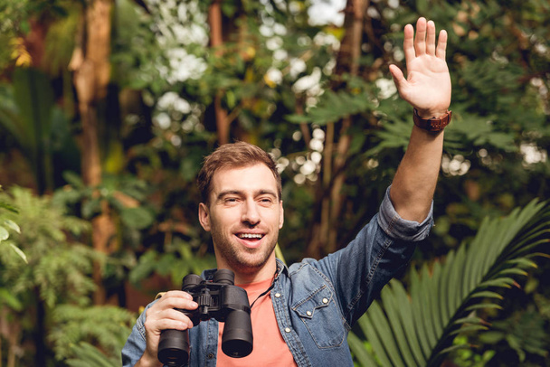 adulto viaggiatore felice con mano in su tenendo binocolo nella foresta verde tropicale
 - Foto, immagini