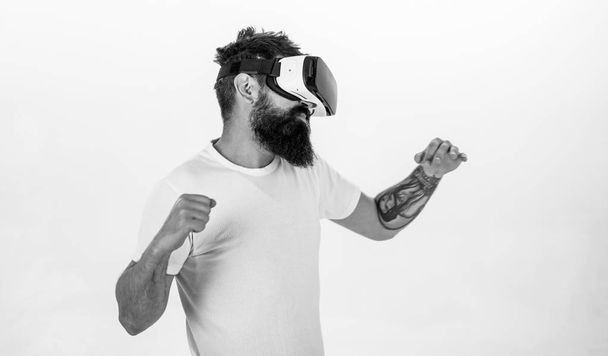 Man with beard in VR glasses fighting, white background. Guy with head mounted display fighting in virtual reality. Virtual battle concept. Hipster on concentrated face beating in virtual reality - Fotografie, Obrázek