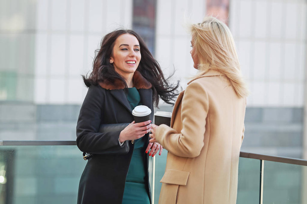 two women walk in the city, drink coffee and enjoy the rest - Photo, image