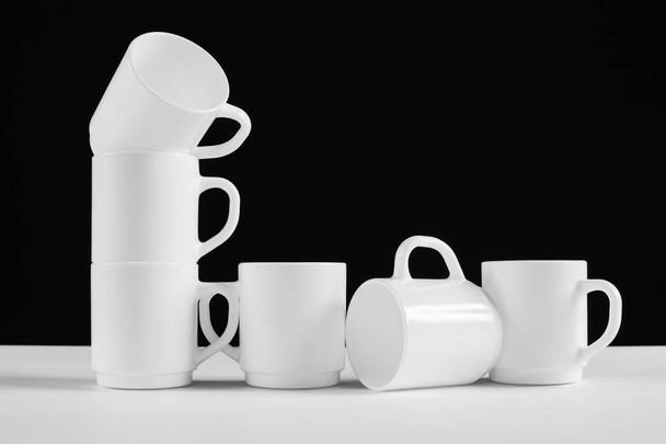 Arrangement of six white mugs with a handle. Black background - Foto, Bild