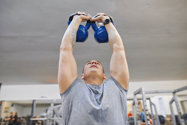 Young strong muscular athlete bodybuilder lifts weights in the gym, weight training - Foto, Bild
