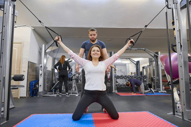 Kyiv UA, 28-03-2019. Mature woman doing exercise on decompression simulators with trainer rehabilitation. Sports physiotherapist assisting aged woman. Kinesio technology, kinesitherapy - Фото, изображение