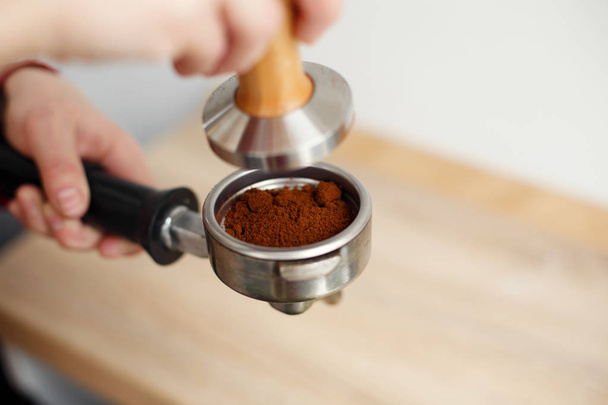 close-up barista hand tamps ground coffee with tamper a into the - Фото, изображение