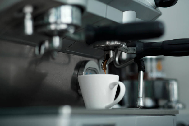 Machinne Kawa rozlewa świeżo parzoną kawę w białe filiżanka - Zdjęcie, obraz