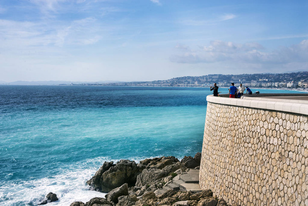 Nice, France, March 2019. Panorama. Azure sea, waves, English promenade and people resting. Rest and relaxation by the sea. On a sunny warm day, blue waves roll. - Foto, imagen