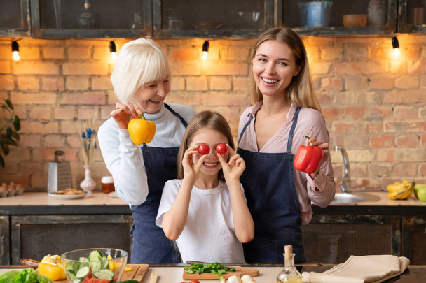 Happy caucasian family having fun with vegetables in kitchen while making healthy dinner - Photo, image