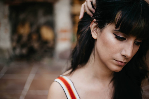 young brunette sad and melancholic girl with black hair pulling hair away from her face - Фото, изображение