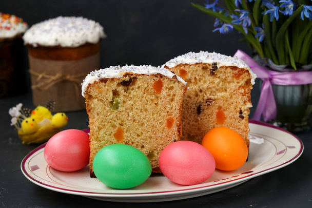 Easter cakes and colorful eggs are located on a plate against a dark background - Foto, Bild