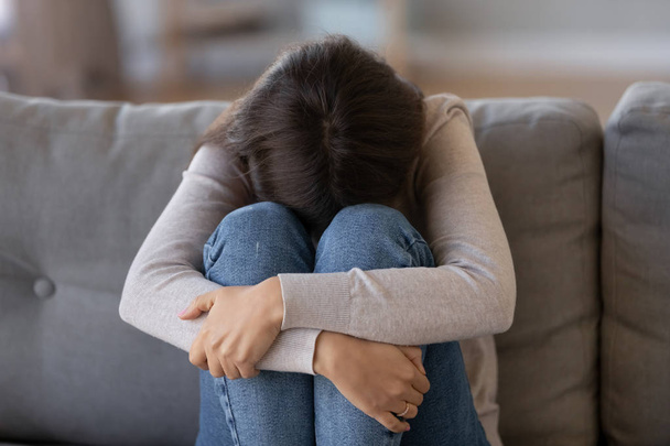 Mujer deprimida sentada en el sofá sintiéndose infeliz llorando sola
 - Foto, Imagen
