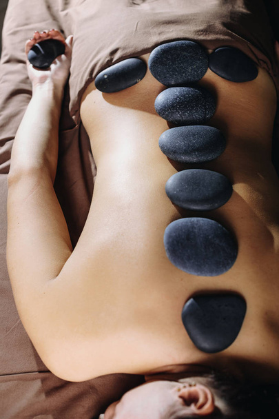 Upper view close up female having stone therapy in a wellness spa. - Photo, Image
