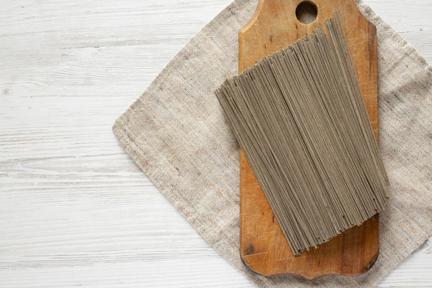 getrocknete Buchweizen-Soba-Nudeln auf rustikalem Holzbrett über weißem - Foto, Bild