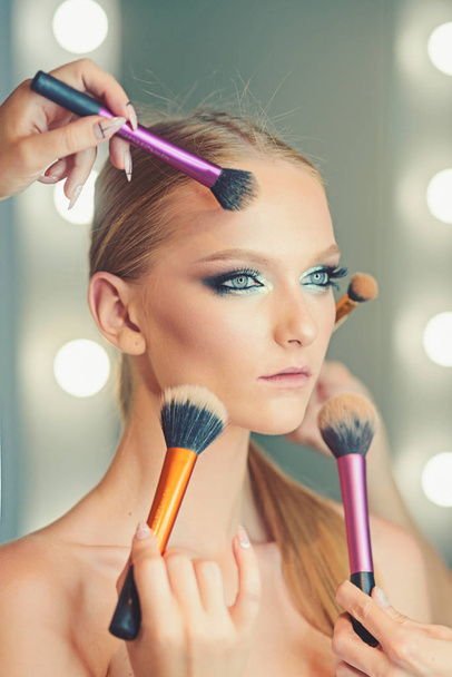 Woman getting powder on skin with makeup brushes. Woman with young face getting makeup in beauty salon - Foto, imagen