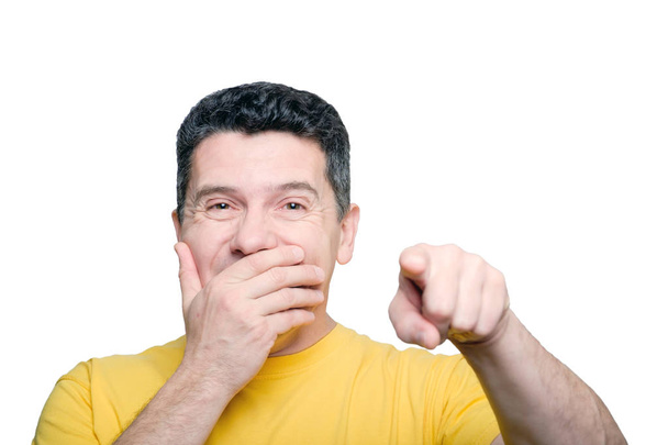 Мужчина среднего возраста закрывает рот рукой и смеется над соперничеством
 - Фото, изображение