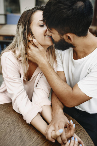 Retrato de una atractiva pareja caucásica cogida de la mano y sentada en el restaurante mientras se besa
. - Foto, imagen