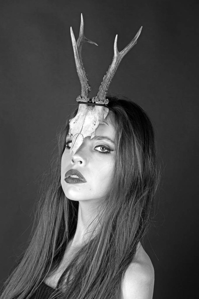 fashionable girl or woman with makeup and antlers. girl in strange skull antlers or horns. - Foto, afbeelding