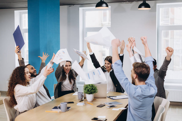 Multiethnic diverse happy team celebrate project success throw paper up together. Corporate community, college graduation, startup activity, salary raise promotion or successful small business concept - Foto, Bild
