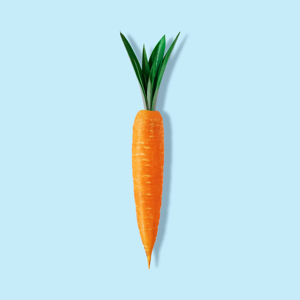 Carrot with pineapple leaves on pastel blue background. Minimal Easter composition. - Foto, Imagem