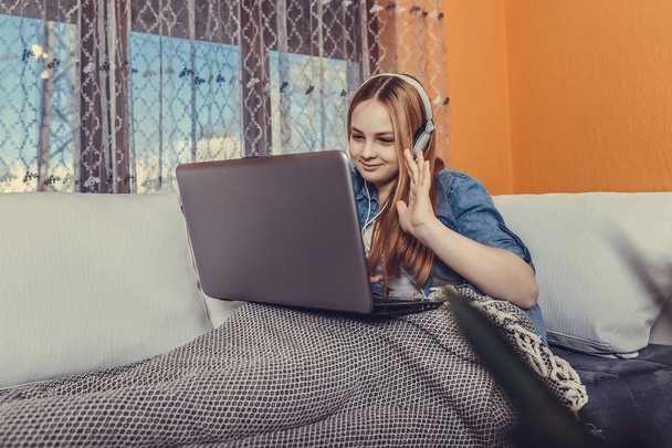 Souriant adolescent fille en utilisant un ordinateur portable pour étudier en ligne à la maison
 - Photo, image
