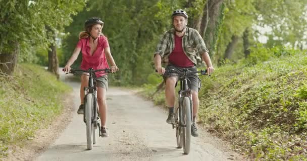 Romantic active couple riding e-bike bicycles mtb on a beutiful outdoor woods path.Wide shot.Friends italian trip in Umbria.4k slow motion - Footage, Video