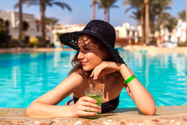 Γυναίκα κατέχει ένα κοκτέιλ στην πισίνα του ξενοδοχείου. Καλοκαιρινές διακοπές. Όλους χωρίς αποκλεισμούς - Φωτογραφία, εικόνα