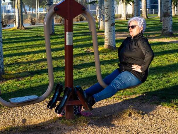Une femme âgée aux cheveux blancs pratiquant la gymnastique dans un parc bio-sain
 - Photo, image