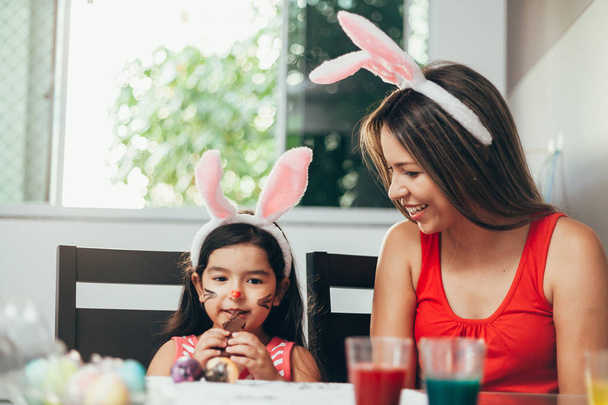 Happy easter! A mother and her daughter painting Easter eggs. Happy family preparing for Easter. Cute little child girl wearing bunny ears on Easter day - Photo, image