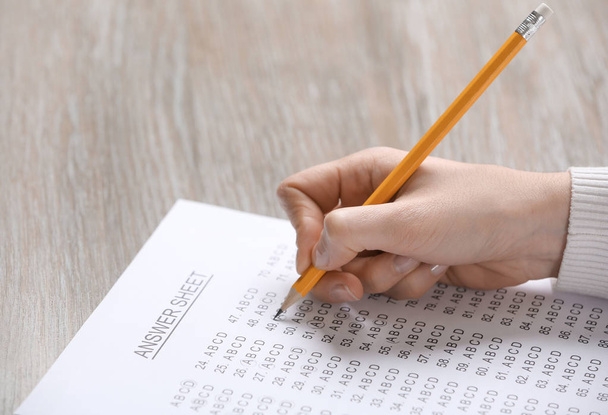Student filling answer sheet at table, closeup - Photo, image