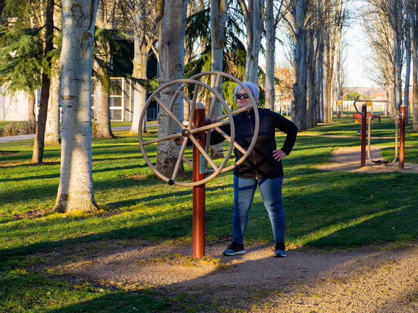 Starší žena s bílými vlasy trénuje gymnastiku v bio-zdravém parku - Fotografie, Obrázek