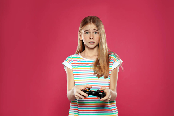 Teenage girl playing video games with controller on color background - Foto, immagini