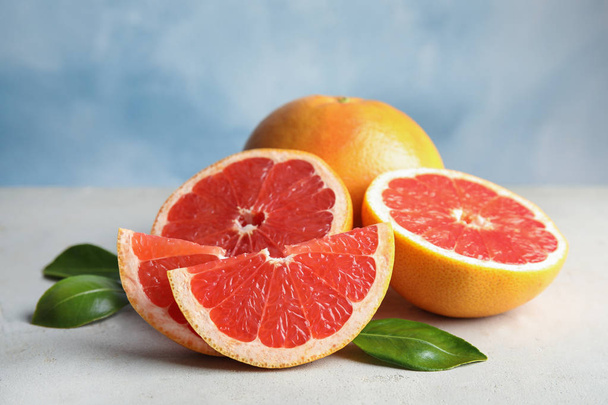 Fresh tasty grapefruits on table against color background - Foto, imagen