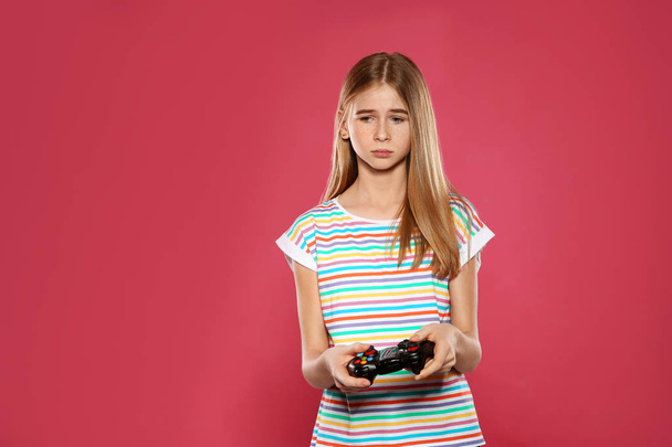 Teenage girl playing video games with controller on color background - Фото, изображение