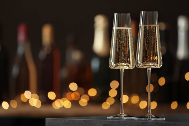 Glasses of champagne on table against blurred background. Space for text - 写真・画像