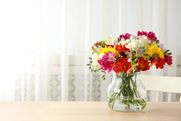 Vase with bouquet of spring freesia flowers on table in room - Foto, Imagem