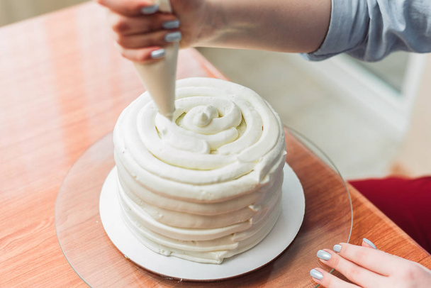 confectioner squeezes the cream on the cake. Girl making a cake - Foto, afbeelding
