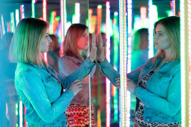 édes kaukázusi lány sétál egy tükör labirintus színes dióda, és élvezi egy szokatlan vonzereje szoba a városban - Fotó, kép