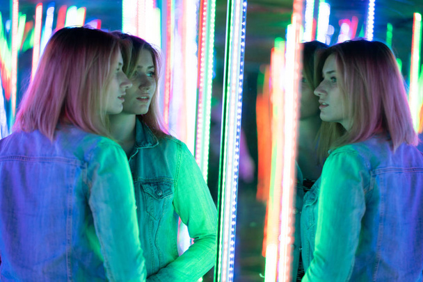 menina caucasiana doce caminha em um labirinto espelho com diodos coloridos e goza de uma sala de atração incomum na cidade
 - Foto, Imagem