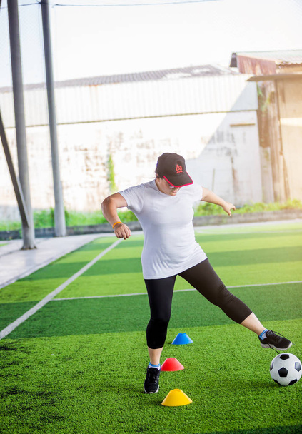 Fußballexpertin joggt und kontrolliert Ball zwischen Kegel - Foto, Bild
