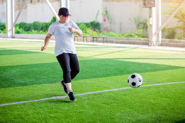 女性のサッカー選手は人工的上の目標にそれを撮影した後ぼやけたボール - 写真・画像