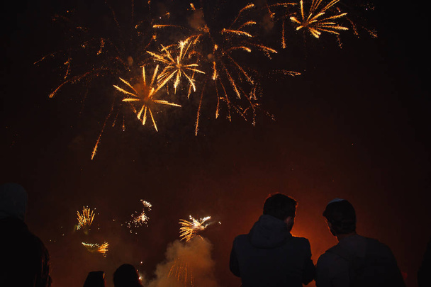 Silhouetten von Menschenmassen, die das Feuerwerk beobachten. Feiern Sie den Feiertag auf dem Platz. Riesenspaß - Foto, Bild