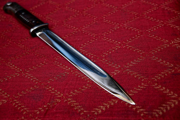 Acute bayonet knife on a red cloth - Photo, Image