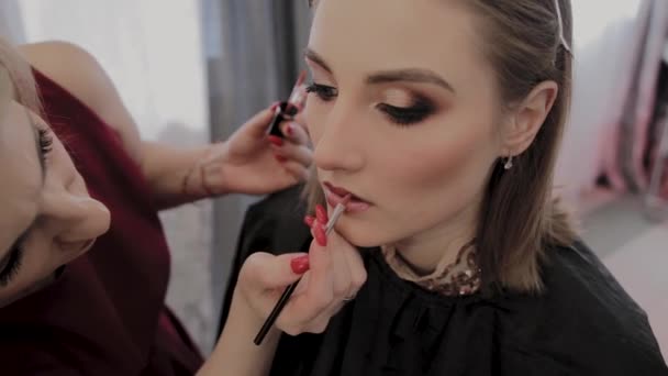 Makeup artist applies professional makeup to a beautiful young girl. New concept in makeup. - Séquence, vidéo