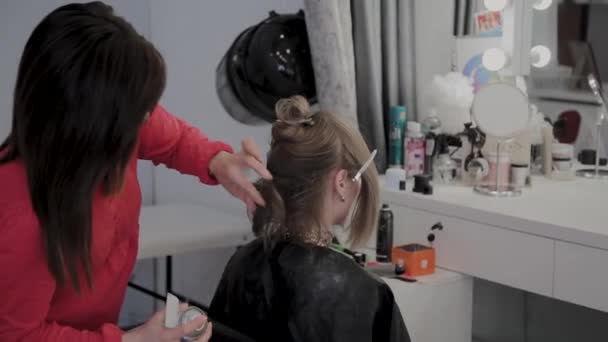 Profesjonalny Fryzjer robi fryzurę dziewczyn na sesję zdjęciową. - Materiał filmowy, wideo