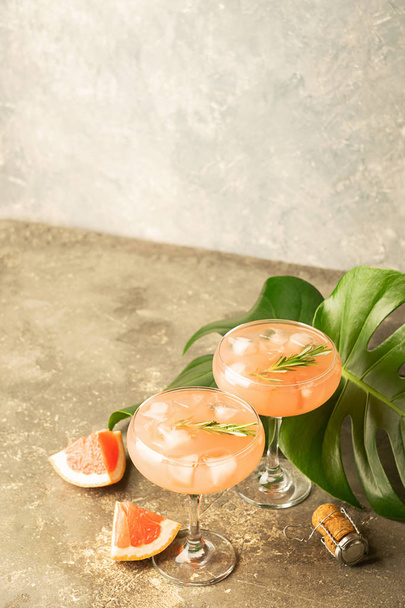Osvěžující letní koktejl grapefruitu šampaňské šťávě skleněné poháry šedé betonové pozadí s monster listy. - Fotografie, Obrázek